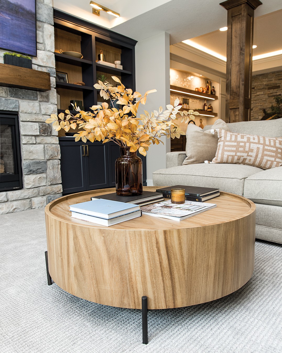 Goldfarb chose a circular coffee table to break up the square lines of the sectional sofa. The table is made with white oak and metal to tie into the shelves surrounding the fireplace.