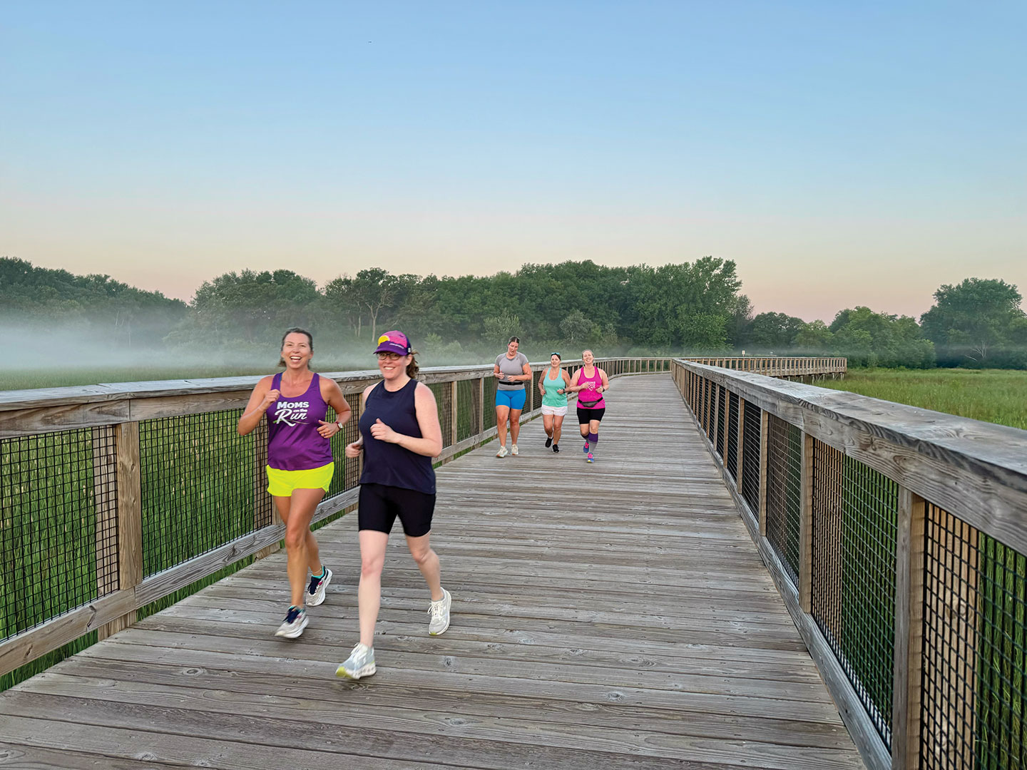 Coach Angie Scheidnes (front left) runs with Liz Potasek (front right) as the sun rises and the fog clears at a sunrise miles class.